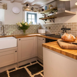 Exemple d'une petit cuisine ouverte nature en U avec un placard avec porte à panneau encastré, des portes de placard marrons, un plan de travail en bois, une crédence grise, une crédence en carreau de céramique, un sol en bambou, aucun îlot et un sol noir.