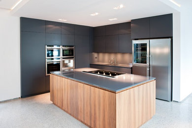 Inredning av ett modernt kök, med en undermonterad diskho, släta luckor, grå skåp, bänkskiva i kvarts, grått stänkskydd och rostfria vitvaror