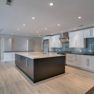 This is an example of a mid-sized beach style single-wall kitchen in Nashville with an undermount sink, flat-panel cabinets, white cabinets, quartzite benchtops, blue splashback, glass tile splashback, stainless steel appliances, linoleum floors and with island.