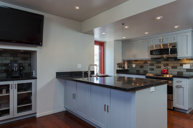 This is an example of a modern kitchen in Salt Lake City with a submerged sink, shaker cabinets, grey cabinets, quartz worktops, grey splashback, glass tiled splashback, stainless steel appliances and medium hardwood flooring.