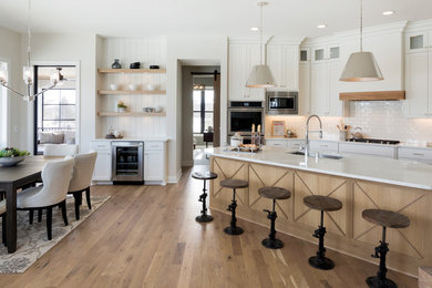 Country u-shaped medium tone wood floor and brown floor eat-in kitchen photo in Minneapolis with an undermount sink, shaker cabinets, white cabinets, white backsplash, subway tile backsplash, stainless steel appliances, an island and white countertops