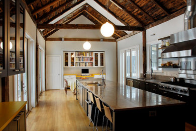 Foto på ett stort funkis kök, med en enkel diskho, släta luckor, skåp i mörkt trä, granitbänkskiva, beige stänkskydd, rostfria vitvaror, mellanmörkt trägolv och en köksö
