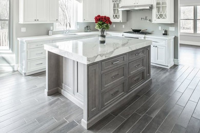 Example of a mid-sized trendy l-shaped ceramic tile eat-in kitchen design in Philadelphia with an undermount sink, marble countertops, stainless steel appliances, an island, shaker cabinets, white cabinets and gray backsplash