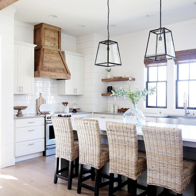 Kitchen - country l-shaped light wood floor and beige floor kitchen idea in Other with a farmhouse sink, shaker cabinets, white cabinets, white backsplash, stainless steel appliances, an island and white countertops
