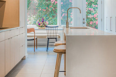 Cette photo montre une cuisine parallèle moderne en bois clair fermée avec un évier posé, un placard à porte plane, un électroménager en acier inoxydable et îlot.