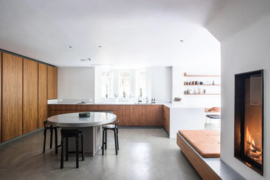 Large contemporary u-shaped open plan kitchen in London with a submerged sink, flat-panel cabinets, quartz worktops, white splashback, stainless steel appliances, concrete flooring, an island, grey floors, white worktops and medium wood cabinets.