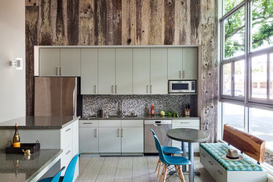 Inspiration for a mid-sized industrial single-wall ceramic tile and gray floor open concept kitchen remodel in San Francisco with an undermount sink, flat-panel cabinets, green cabinets, quartz countertops, multicolored backsplash, mosaic tile backsplash, stainless steel appliances, an island and gray countertops