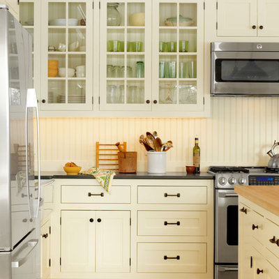 Example of a classic kitchen design in Burlington with glass-front cabinets, yellow cabinets, wood countertops and stainless steel appliances