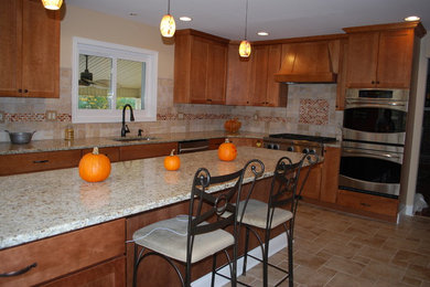 Example of a transitional l-shaped eat-in kitchen design in Philadelphia with an undermount sink, flat-panel cabinets, light wood cabinets, granite countertops, beige backsplash, stainless steel appliances and an island