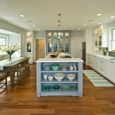 Inspiration for a mid-sized tropical medium tone wood floor eat-in kitchen remodel in Hawaii with an integrated sink, shaker cabinets, white cabinets, solid surface countertops, blue backsplash, glass tile backsplash, paneled appliances and an island