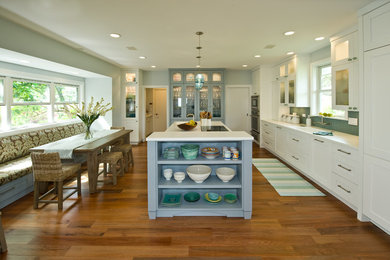 Inspiration for a mid-sized tropical medium tone wood floor eat-in kitchen remodel in Hawaii with an integrated sink, shaker cabinets, white cabinets, solid surface countertops, blue backsplash, glass tile backsplash, paneled appliances and an island