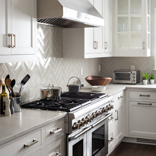 Mid-sized transitional open concept kitchen designs - Example of a mid-sized transitional l-shaped dark wood floor open concept kitchen design in New York with an undermount sink, shaker cabinets, white cabinets, quartzite countertops, gray backsplash, ceramic backsplash, stainless steel appliances and an island