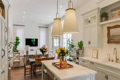 Inspiration for a mid-sized french country u-shaped medium tone wood floor and beige floor eat-in kitchen remodel in Los Angeles with an undermount sink, recessed-panel cabinets, white cabinets, marble countertops, white backsplash, marble backsplash, white appliances, an island and white countertops