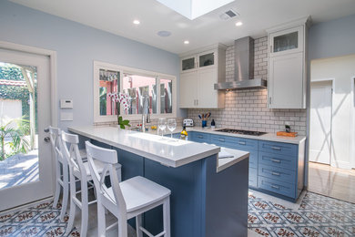 Design ideas for a medium sized traditional u-shaped enclosed kitchen in Los Angeles with shaker cabinets, blue cabinets, white splashback, metro tiled splashback, a breakfast bar, multi-coloured floors, white worktops, a submerged sink, limestone worktops, stainless steel appliances and ceramic flooring.