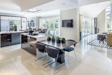 This is an example of a contemporary open plan kitchen in Berkshire with flat-panel cabinets, multiple islands, porcelain flooring and a submerged sink.