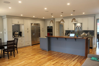 Open concept kitchen - large modern l-shaped light wood floor and brown floor open concept kitchen idea in Other with an undermount sink, shaker cabinets, gray cabinets, granite countertops, blue backsplash, porcelain backsplash, stainless steel appliances, an island and gray countertops