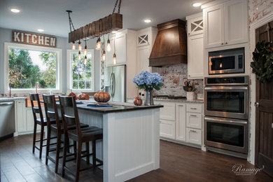 Open concept kitchen - large transitional u-shaped brown floor open concept kitchen idea in Other with a farmhouse sink, shaker cabinets, white cabinets, granite countertops, multicolored backsplash, brick backsplash, stainless steel appliances, an island and gray countertops