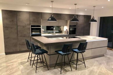 Photo of a large contemporary single-wall kitchen/diner in Cheshire with grey cabinets, grey splashback, mirror splashback, integrated appliances, porcelain flooring, an island, grey floors, grey worktops and a built-in sink.