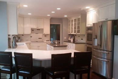 Example of a large classic u-shaped medium tone wood floor kitchen design in Other with an undermount sink, white backsplash, subway tile backsplash, raised-panel cabinets, white cabinets and an island