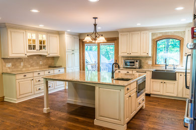 Large arts and crafts l-shaped medium tone wood floor and brown floor eat-in kitchen photo in Other with a farmhouse sink, recessed-panel cabinets, distressed cabinets, quartz countertops, gray backsplash, marble backsplash, stainless steel appliances, an island and gray countertops
