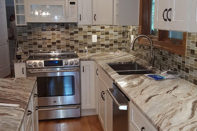 Kitchen - large transitional u-shaped medium tone wood floor kitchen idea in Richmond with an island, an undermount sink, recessed-panel cabinets, white cabinets, granite countertops, gray backsplash, glass tile backsplash and stainless steel appliances