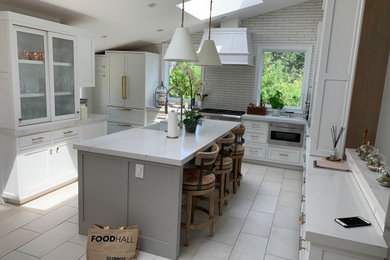 Eat-in kitchen - large transitional u-shaped ceramic tile, gray floor and vaulted ceiling eat-in kitchen idea in San Francisco with a farmhouse sink, shaker cabinets, white cabinets, quartz countertops, white backsplash, subway tile backsplash, paneled appliances, an island and white countertops