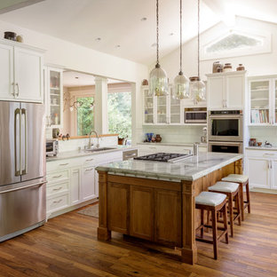 Idee per una cucina chic con lavello sottopiano, ante in stile shaker, ante bianche, paraspruzzi bianco, elettrodomestici in acciaio inossidabile, pavimento in legno massello medio, isola e pavimento marrone