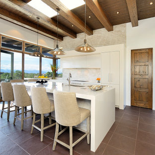 Idee per una cucina a L stile americano chiusa e di medie dimensioni con lavello a vasca singola, ante lisce, ante beige, paraspruzzi beige, paraspruzzi in lastra di pietra, elettrodomestici da incasso, isola, pavimento grigio, top in superficie solida e travi a vista