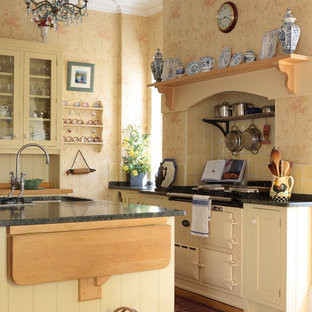 Photo of a traditional l-shaped kitchen in Other with a submerged sink, recessed-panel cabinets, yellow cabinets, yellow splashback, coloured appliances, medium hardwood flooring, an island and brown floors.
