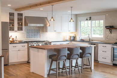 Example of a mid-sized farmhouse u-shaped light wood floor and brown floor eat-in kitchen design in Los Angeles with an undermount sink, beaded inset cabinets, white cabinets, limestone countertops, white backsplash, subway tile backsplash, stainless steel appliances, an island and gray countertops