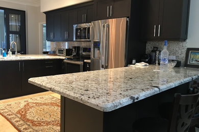 Example of a mid-sized u-shaped porcelain tile eat-in kitchen design in Miami with shaker cabinets, dark wood cabinets, granite countertops, multicolored backsplash, stone slab backsplash, stainless steel appliances and no island