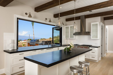 Inspiration for a large coastal u-shaped light wood floor and brown floor open concept kitchen remodel in Hawaii with an undermount sink, shaker cabinets, white cabinets, white backsplash, paneled appliances, an island, solid surface countertops and subway tile backsplash