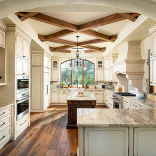 Ispirazione per una cucina ad U classica con lavello stile country, ante con riquadro incassato, ante con finitura invecchiata, paraspruzzi beige, elettrodomestici in acciaio inossidabile, pavimento in legno massello medio, pavimento marrone e top beige