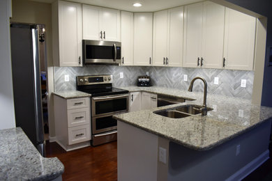Inspiration for a mid-sized contemporary u-shaped medium tone wood floor and brown floor kitchen remodel in DC Metro with a double-bowl sink, shaker cabinets, white cabinets, granite countertops, gray backsplash, ceramic backsplash, stainless steel appliances and multicolored countertops