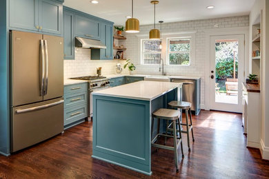 Enclosed kitchen - mid-sized traditional l-shaped dark wood floor and brown floor enclosed kitchen idea in Portland with a farmhouse sink, recessed-panel cabinets, blue cabinets, quartzite countertops, white backsplash, subway tile backsplash, stainless steel appliances, an island and white countertops