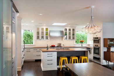 Inspiration for a mid-sized contemporary u-shaped dark wood floor and brown floor eat-in kitchen remodel in Seattle with an undermount sink, shaker cabinets, white cabinets, wood countertops, white backsplash, ceramic backsplash, stainless steel appliances and an island