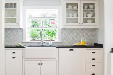 Large elegant medium tone wood floor kitchen photo in Seattle with a farmhouse sink, white cabinets, granite countertops, gray backsplash, glass tile backsplash, stainless steel appliances, no island and glass-front cabinets