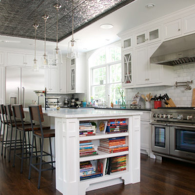 Inspiration for a large transitional l-shaped medium tone wood floor and brown floor kitchen remodel in San Luis Obispo with an undermount sink, recessed-panel cabinets, white cabinets, gray backsplash, stainless steel appliances, an island and black countertops