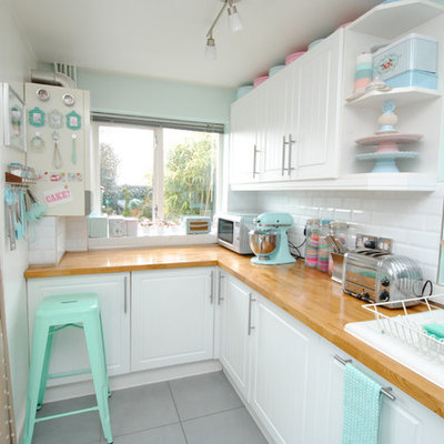 Example of a beach style kitchen design in Devon with subway tile backsplash and wood countertops