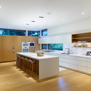 Idee per una grande cucina moderna con lavello sottopiano, ante lisce, ante bianche, top in superficie solida, paraspruzzi bianco, elettrodomestici bianchi e parquet chiaro