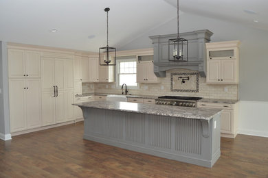Inspiration for a mid-sized timeless u-shaped vinyl floor and brown floor eat-in kitchen remodel in Philadelphia with a farmhouse sink, raised-panel cabinets, beige cabinets, granite countertops, beige backsplash, travertine backsplash, stainless steel appliances, an island and multicolored countertops