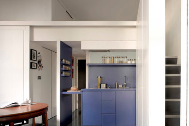 This is an example of a small contemporary open plan kitchen in London with a built-in sink, flat-panel cabinets, blue cabinets, stainless steel appliances, ceramic flooring and blue splashback.