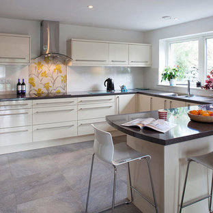 Small contemporary u-shaped kitchen in Cornwall with an integrated sink, flat-panel cabinets, white cabinets, solid surface benchtops, white splashback, ceramic floors and a peninsula.