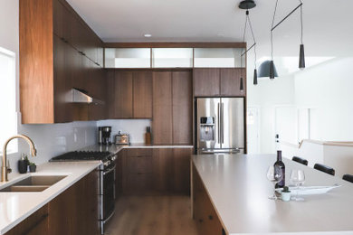 Immagine di una cucina con ante lisce, ante in legno scuro, top in quarzite, elettrodomestici in acciaio inossidabile e parquet chiaro