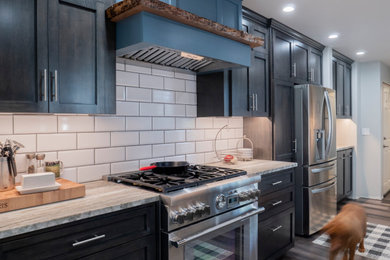 Diseño de cocina comedor moderna de tamaño medio con puertas de armario negras, encimera de mármol, salpicadero blanco, salpicadero de azulejos tipo metro, electrodomésticos de acero inoxidable y encimeras verdes