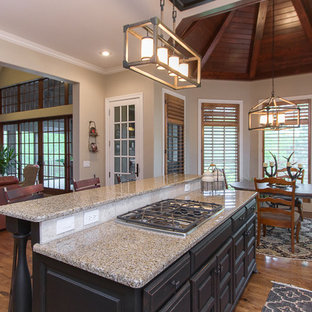 Large rustic open concept kitchen remodeling - Example of a large mountain style l-shaped medium tone wood floor and brown floor open concept kitchen design in Kansas City with an undermount sink, raised-panel cabinets, dark wood cabinets, terrazzo countertops, beige backsplash, ceramic backsplash, stainless steel appliances and an island