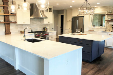 Eat-in kitchen - large transitional u-shaped vinyl floor and brown floor eat-in kitchen idea in Other with a single-bowl sink, shaker cabinets, white cabinets, quartz countertops, white backsplash, porcelain backsplash, stainless steel appliances, an island and white countertops