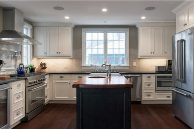 ワシントンD.C.にある広いトラディショナルスタイルのおしゃれなアイランドキッチン (エプロンフロントシンク、落し込みパネル扉のキャビネット、白いキャビネット、木材カウンター、グレーのキッチンパネル、サブウェイタイルのキッチンパネル、シルバーの調理設備、濃色無垢フローリング、茶色い床) の写真