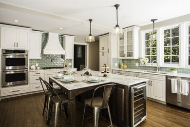 Example of a large transitional l-shaped dark wood floor and brown floor enclosed kitchen design in New York with an undermount sink, raised-panel cabinets, white cabinets, marble countertops, green backsplash, subway tile backsplash, stainless steel appliances and an island