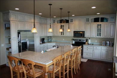 Inspiration för ett mellanstort vintage kök, med en dubbel diskho, luckor med upphöjd panel, vita skåp, granitbänkskiva, rostfria vitvaror, mörkt trägolv, en köksö och brunt golv